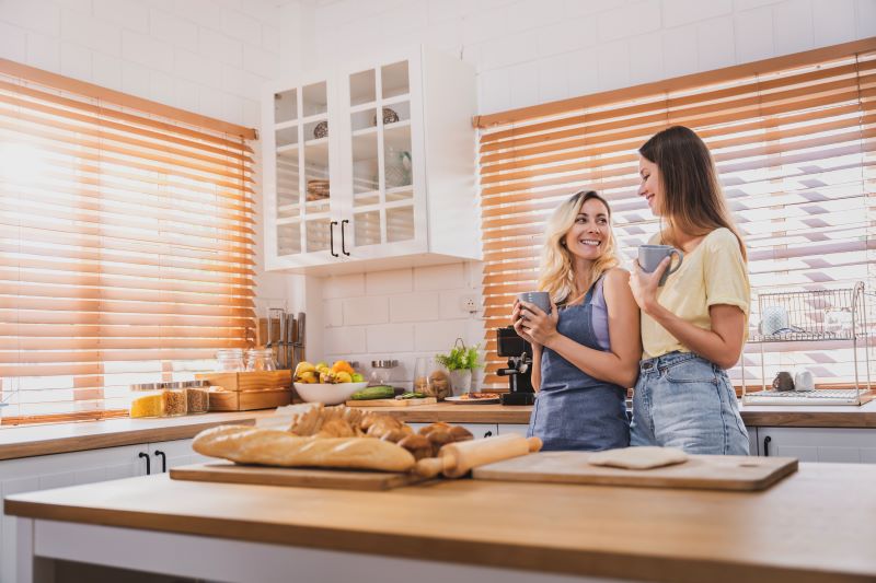 dwie kobiety w kuchni z żaluzjami drewnianymi